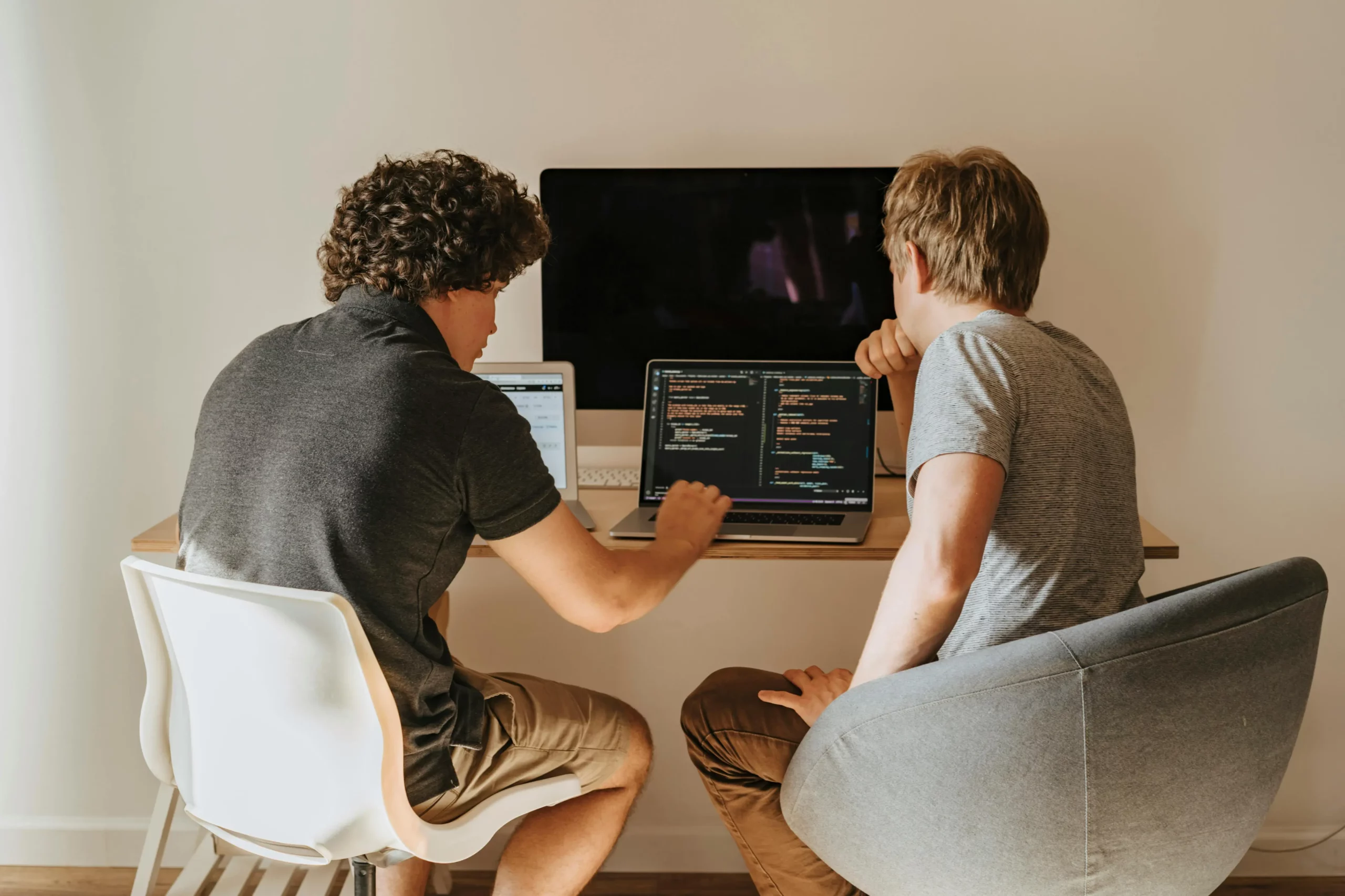 Two men reviewing code on a laptop